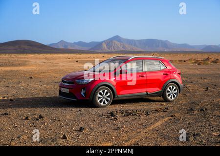 Roter SUV parkt auf einem Wüstenflachland in der Nähe von Playa de la Escalera (Staircase Beach) an der Westküste von Fuerteventura auf den Kanarischen Inseln, Atlantik Stockfoto