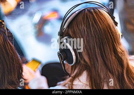 Eine junge Frau, die in einem professionellen Umfeld Studiokopfhörer trägt. Stockfoto