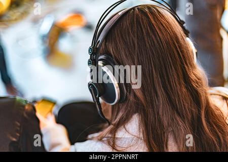 Eine junge Frau, die in einem professionellen Umfeld Studiokopfhörer trägt. Stockfoto