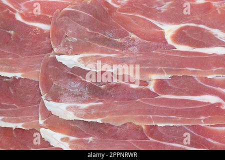 Jamon serrano. Ein spanischer Schinken-Hintergrund. Traditioneller spanischer Jamon in Scheiben. Trocken gepökelter Fleischschinken. Hamon iberico Stockfoto