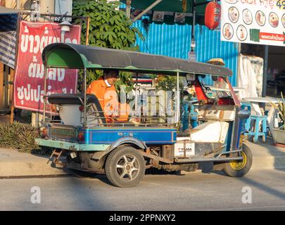 SAMUT PRAKAN, THAILAND, 28 2023. JANUAR, Ein Mann im Overall sitzt in einem Tuk-Tuk-Dreirad, das auf der Straße parkt Stockfoto