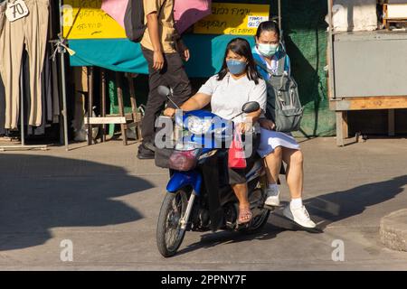 SAMUT PRAKAN, THAILAND, FEBRUAR 07 2023, zwei Frauen fahren mit dem Motorrad auf der Straße mit Ständen. Stockfoto