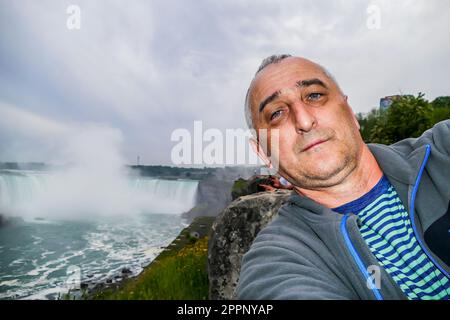 NIAGARAFÄLLE, ONTARIO, KANADA - 29. MAI 2016: Selfie von Männern mit Niagarafällen und Wasserfall Stockfoto