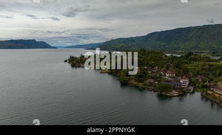 Blick aus der Vogelperspektive auf den Touristenort Tuk Tuk am Lake Toba und die Küste der Insel Samosir. Sumatra, Indonesien. Tropische Landschaft. Stockfoto