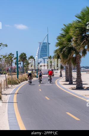 Drei Radfahrer fahren auf dem Radweg am öffentlichen Strand Jumeirah Wild in Dubai, Vereinigte Arabische Emirate Stockfoto