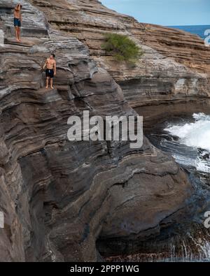 Ein Mann, der von der Spitting Cave auf Oahu, Hawaii, springt. Hochwertiges Foto Stockfoto