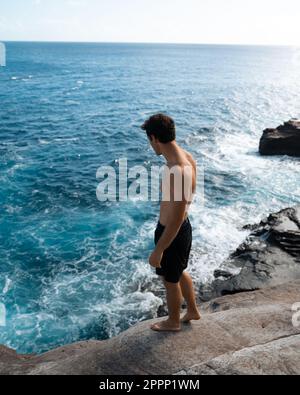 Ein Mann, der von der Spitting Cave auf Oahu, Hawaii, springt. Hochwertiges Foto Stockfoto