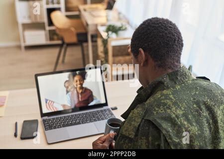 Rückansicht eines Militärvaters, der während seines Kriegsdienstes online mit seiner Familie über einen Laptop spricht Stockfoto