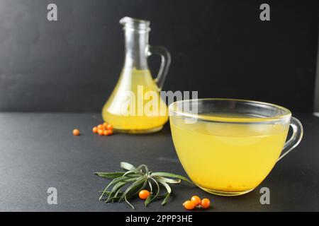 Sanddorn Tee gelbe Limonade aus Sanddorn iago auf schwarzem Hintergrund in einem Glasbecher. Vitamin C. heiße Herbstgetränke. Stockfoto