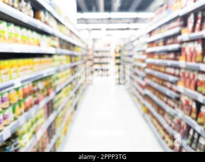 Verschwommener Hintergrund mit Supermarkt. Verschwommener Hintergrund des Interieurs des Supermarkts mit Einkaufswagen. Halle oder Einkaufszentrum mit verschwommenen Lichtern hinten Stockfoto