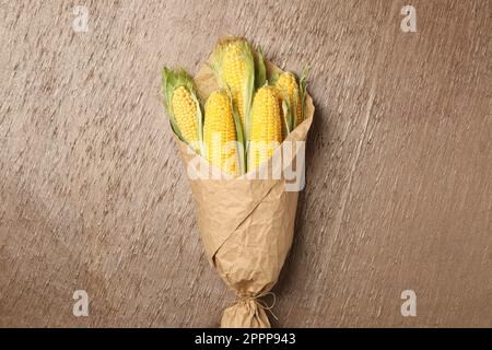 Maiskolben in Pergament auf dem Tisch gewickelt, Draufsicht Stockfoto