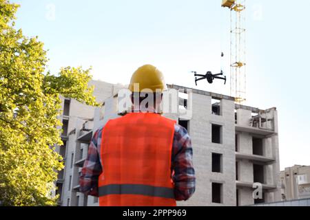 Bauarbeiter, die Drohne mit Fernsteuerung auf der Baustelle bedienen. Luftaufnahmen Stockfoto