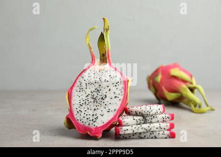 Köstliche geschnittene Drachenfrüchte (Pitahaya) auf einem grauen Tisch Stockfoto