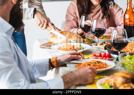 Tischset mit Spaghetti und Gläsern Wein. Anonyme gesichtslose Menschen Stockfoto