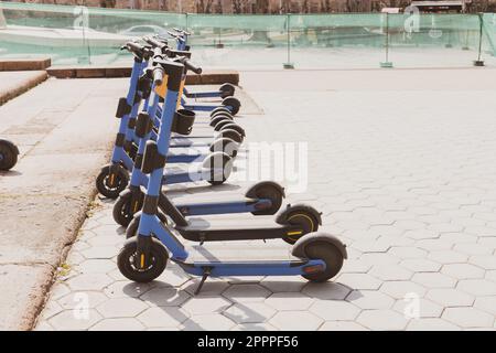 In der Stadt geparkte elektrische Roller - moderne batteriebetriebene Mietfahrzeuge für den Personenverkehr - neue Trends der nachhaltigen Stadtentwicklung Stockfoto