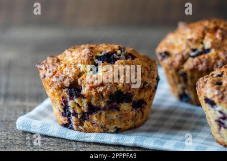 Köstliche Muffins mit Blaubeeren auf einem Holztisch, Nahaufnahme. Süßes Gebäck auf dem Brett. Frische Cupcakes zum Frühstück Stockfoto