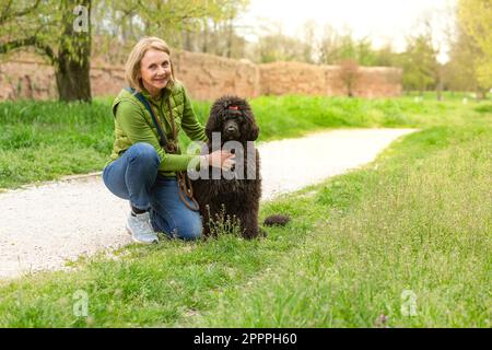 Porträt einer lächelnden, reifen Dame mit ihrem Hund im Park. Konzept von Gesundheit, Outdoor-Aktivitäten und gesundem Lebensstil mit Ihren Haustieren Stockfoto