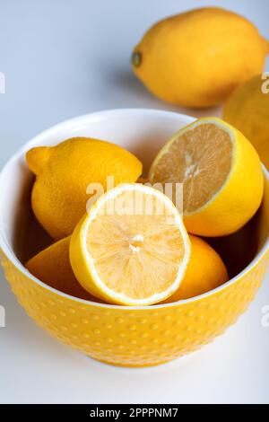 Zitronen in einer Schüssel, ganz und halbiert. Nahaufnahme. Stockfoto