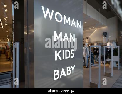 Eingang des Bekleidungsgeschäfts im Einkaufszentrum, mit Text-Brett „Frau, Mann, Kinder, Baby“. Stockfoto