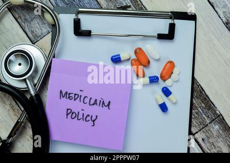 Konzept der Mediclaim-Politik Schreiben auf Haftnotizen mit Stethoskop isoliert auf Holztisch. Stockfoto