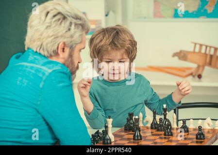 Glücklicher Vater und Sohn. Spiele und Aktivitäten für Kinder. Männerlehrer spielt Schach mit Vorschulkind. Stockfoto