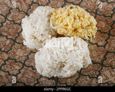 Weißer und gelber Kakao auf brauner Keramikplatte - Blick von oben, traditionelle brasilianische Kokosnuss süß. Stockfoto