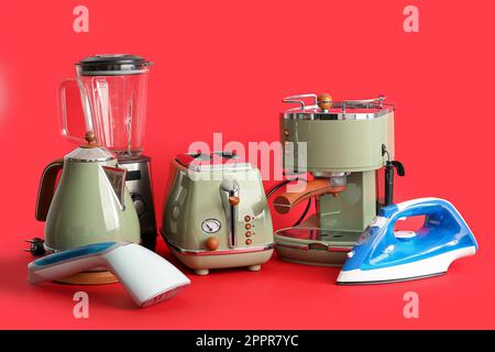 Satz moderner Haushaltsgeräte auf rotem Hintergrund Stockfoto