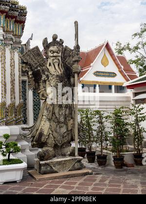 Eine historische chinesische Kriegerstatue aus Stein, die sich im ruhigen buddhistischen Tempel Wat Pho im belebten Bangkok, Thailand, befindet. Die alte Handwerksmannshi Stockfoto