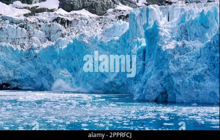 Nahaufnahme eines Gletschergesichts, während ein Eisstück nach dem Abkalben ins Wasser spritzt. In Drygalski Fjord auf South Georgia Island. Stockfoto