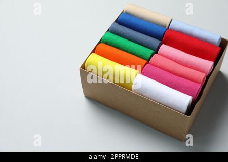 Box mit verschiedenen bunten Socken auf hellem Hintergrund. Platz für Text Stockfoto