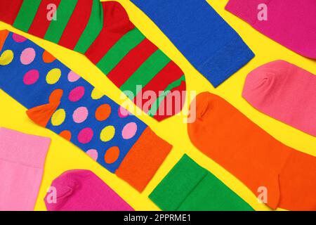 Viele verschiedene bunte Socken auf gelbem Hintergrund, flach liegend Stockfoto