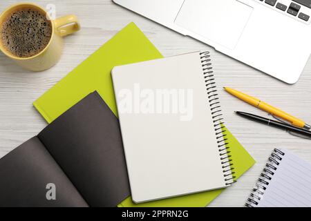 Flache Liegezusammensetzung mit verschiedenen Notizbüchern, Kaffee und Stiften auf Holztisch Stockfoto