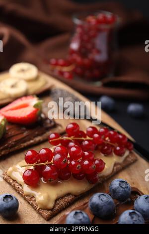 Frisches knuspriges Roggen-Knusperbrot mit verschiedenen Belägen auf Holzbrett, Nahaufnahme Stockfoto