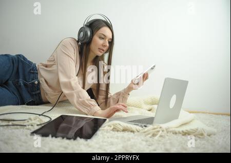 Lächelnde Schülerin trägt kabellose Kopfhörer Studie online mit skype-Lehrerin glückliche junge Frau erlernen Sprache Hören Sie Vorlesung Sehen Sie sich das Webinar an Schreiben Sie Notizen über die Ausbildung von Notebooks in der Ferne Stockfoto