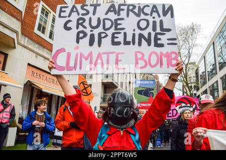 London, Großbritannien. 24. April 2023. Ein Protestteilnehmer, der eine Stop-EACOP-Maske (East African Crude Oil Pipeline) trägt, hält am letzten Tag der Demonstrationen in Westminster einen Anti-EACOP-Plakat. Extinction Rebellion und mehrere andere Aktivistengruppen veranstalten einen letzten Protest, in dem ein Ende der fossilen Brennstoffe gefordert wird. (Foto: Vuk Valcic/SOPA Images/Sipa USA) Guthaben: SIPA USA/Alamy Live News Stockfoto