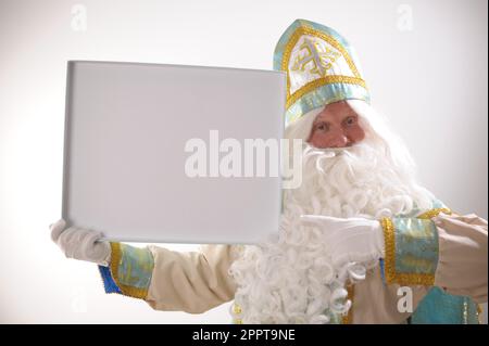 Der Weihnachtsmann ist überrascht, als er dabei erwischt wird, einen Kinderstrumpf zu stopfen. Isoliert auf weiß. Hochwertiges Foto Stockfoto
