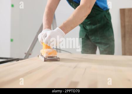 Erfahrener Zimmermann poliert die Holzoberfläche des Bürotischs Stockfoto
