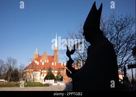 Breslau, Polen. 22. April 2023. Ein Denkmal für Kardinal Kominek auf Sand Island vor der Kathedrale von Breslau, der Kathedrale von St. Johannes der Täufer der Erzdiözese von Breslau. Kredit: Sebastian Kahnert/dpa/Alamy Live News Stockfoto