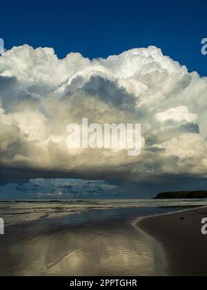 Dramatische, tief hängende Cumulonimbus-Wolke, die über dem Strand schwebt und einen unheilvollen Schatten wirft, der sich auf dem Meer spiegelt, Coffs Harbour, NSW Australien Stockfoto