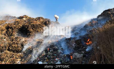Toxischer Rauch auf Deponien: Sanitäter sortieren Müll unter Umweltgefahren Stockfoto