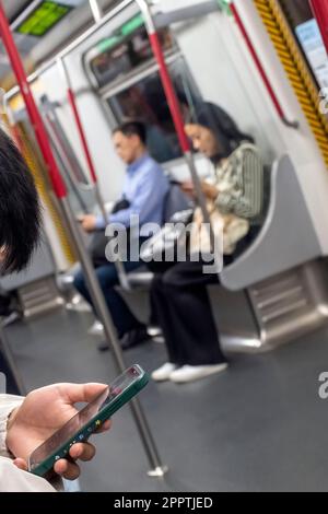 Passagiere, die Verwendung von Mobiltelefonen in der u-Bahn MTR Hong Kong, Hong Kong, China. Stockfoto