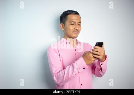 Asiatischer junger Mann mit pinkfarbenem Hemd und Gesichtsausdruck. Stockfoto