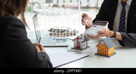 Immobilienmakler sprechen mit Kunden und bieten gute Zinssätze an und berechnen Kunden über Hypothekenfinanzierungen, um ihnen bei der Entscheidung über Immobilienvorschläge zu helfen Stockfoto