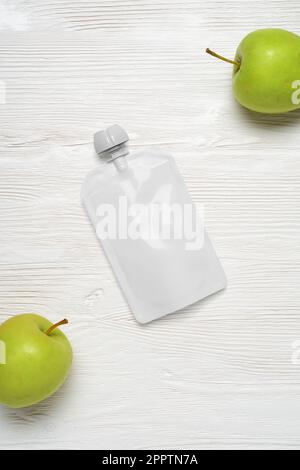 Weißer leerer Plastikbeutel für Babynahrung, Fruchtpüree auf Holztisch. Modellvorlage für Konstruktion. 3D-Rendering-Abbildung. Stockfoto