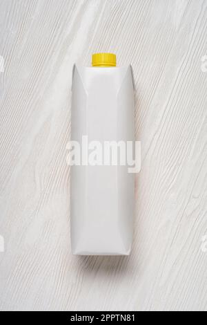 Weiße Packung mit Saft oder Milch auf einem Holztisch. Modellvorlage. Stockfoto