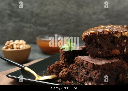 Köstliche Schokoladenbrownies mit Nüssen, Karamellsauce und frischer Minze auf dem Teller, Nahaufnahme Stockfoto