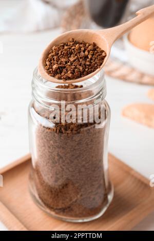 Löffel Instantkaffee über dem Glas auf dem weißen Tisch Stockfoto