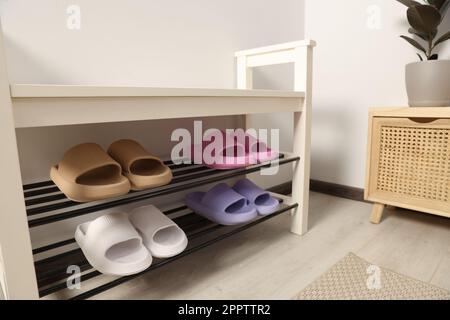 Aufbewahrungsbank mit Paar Gummipantoffeln im Zimmer Stockfoto