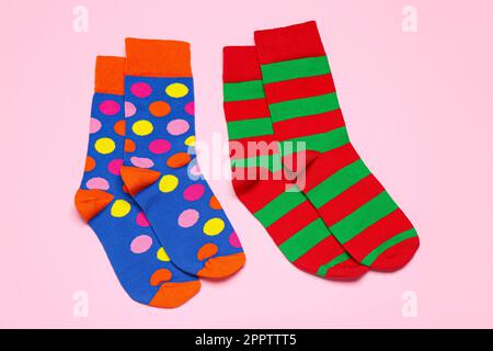 Verschiedene bunte Socken auf hellrosa Hintergrund, flach liegend Stockfoto