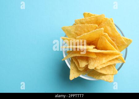 Tortilla-Chips (Nachos) in Glasschüssel auf hellblauem Hintergrund, Draufsicht. Platz für Text Stockfoto